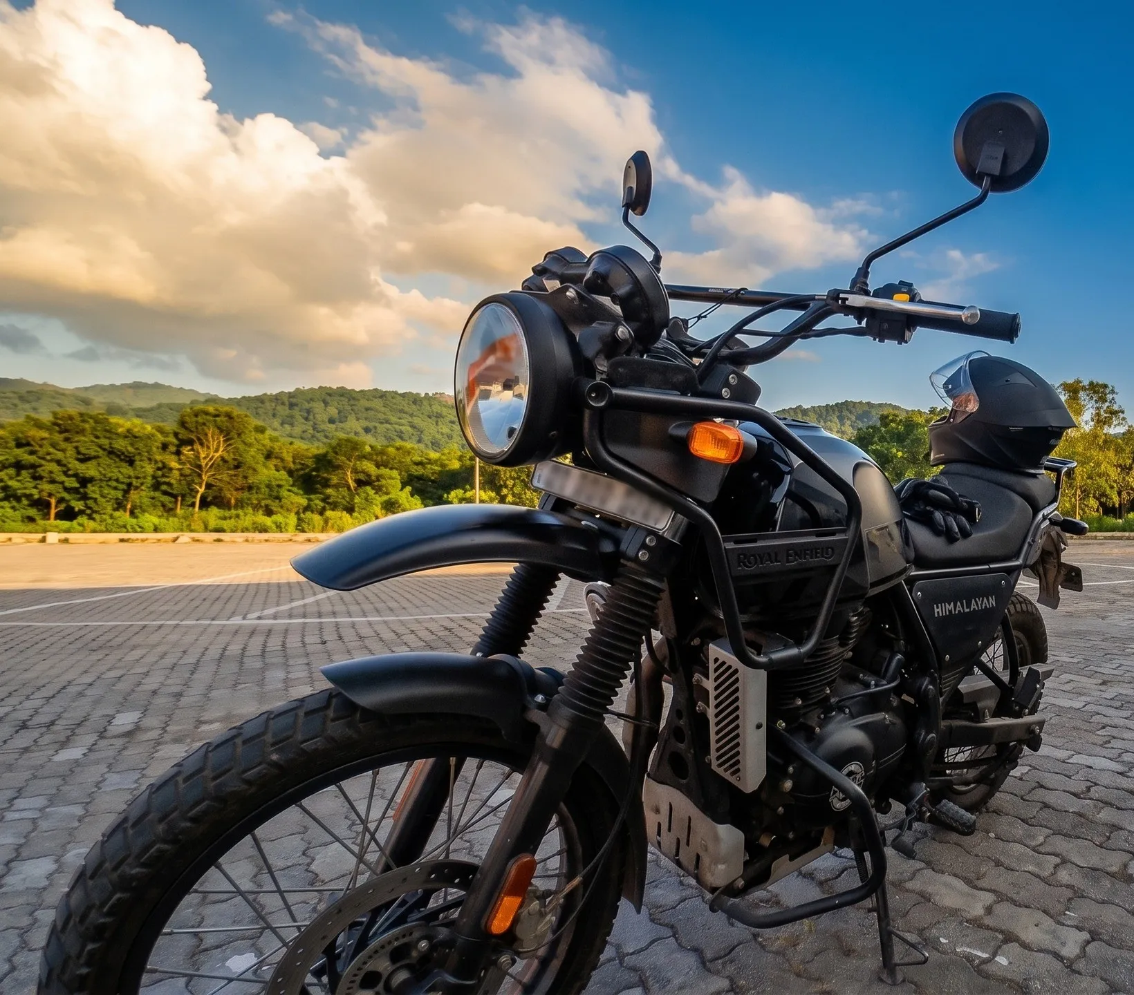 Himalati, a black Himalayan 440, on cobblestones under a blue sky with green hills behind